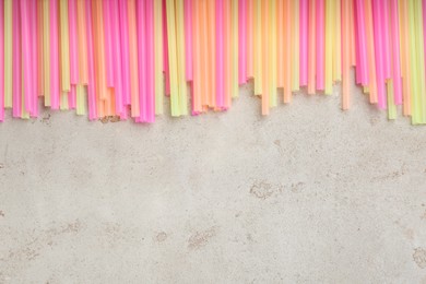 Colorful plastic drinking straws on grey stone table, flat lay. Space for text