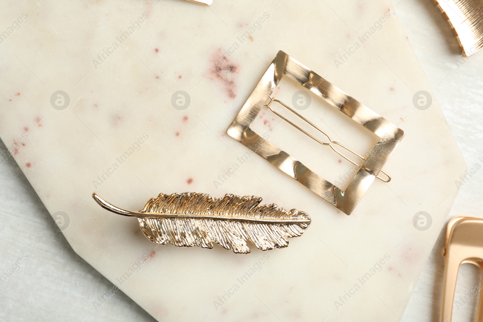 Photo of Beautiful gold hair clips on marble board, flat lay