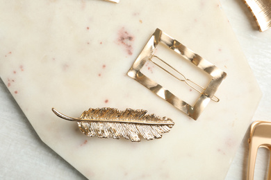 Photo of Beautiful gold hair clips on marble board, flat lay