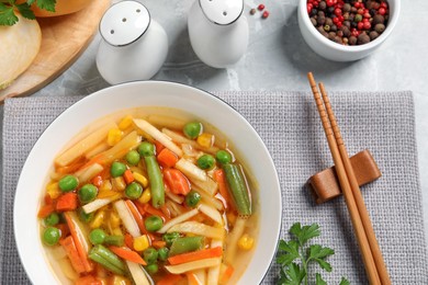 Photo of Bowl of delicious turnip soup served on light table, flat lay