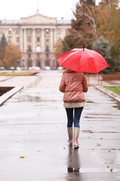 Woman with umbrella taking autumn walk in city on rainy day