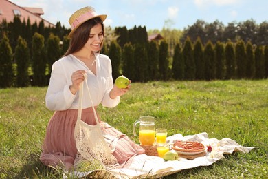 Photo of Young woman with green apples having picnic outdoors on summer day