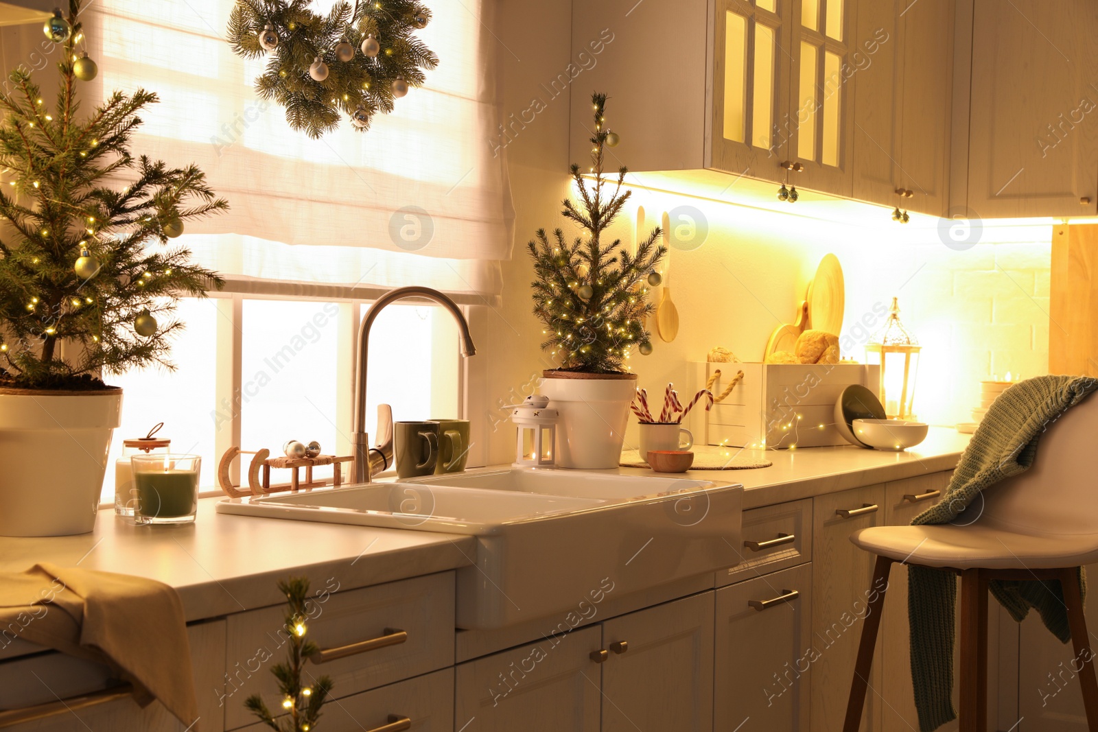 Photo of Small Christmas trees and festive decor in kitchen