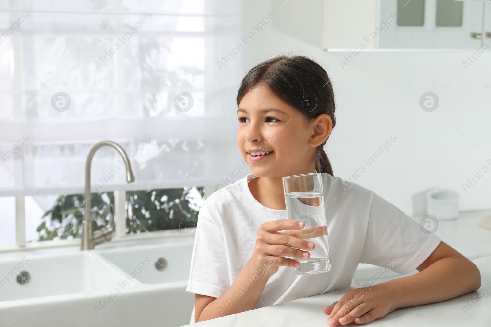 Photo of Girl with glass of tap water in kitchen