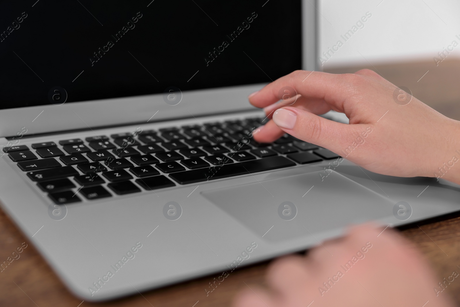 Photo of Woman working on laptop at wooden table closeup. Electronic document management