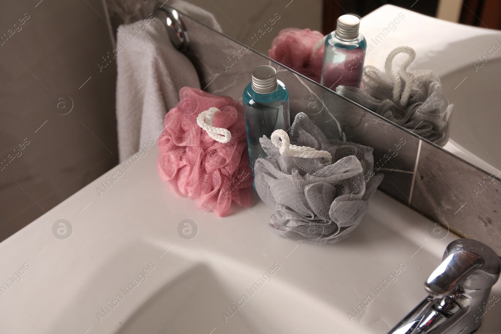 Photo of Colorful sponges between shower gel bottle on sink in bathroom