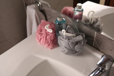 Colorful sponges between shower gel bottle on sink in bathroom