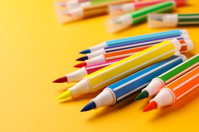 Photo of Many bright markers on yellow background, closeup. Space for text