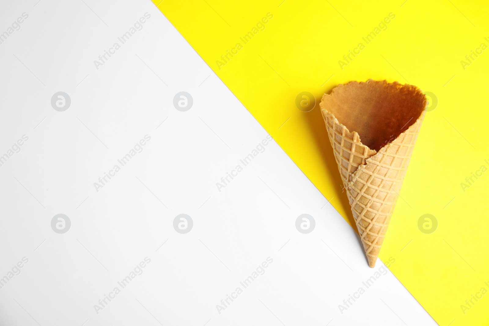 Photo of Empty wafer ice cream cone on color background, top view. Space for text