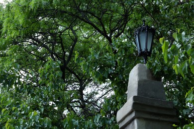 Elegant street lamp on stone parapet in park, low angle view. Space for text