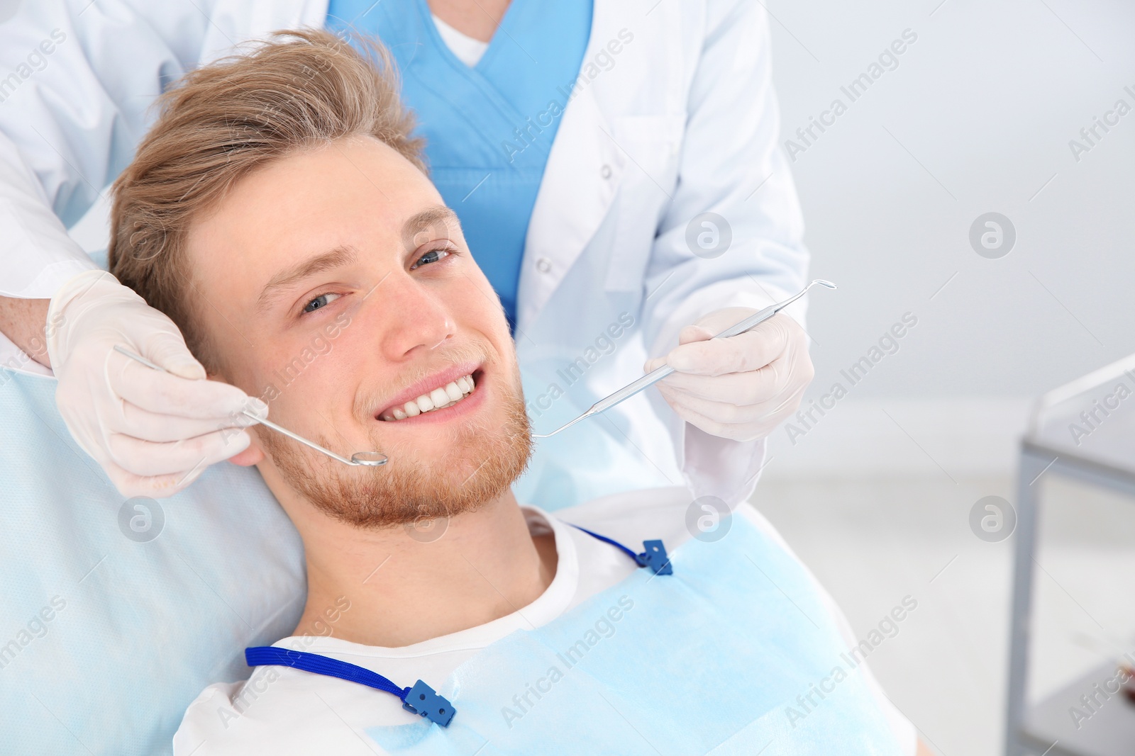 Photo of Dentist examining patient's teeth in modern clinic