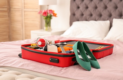 Photo of Open travel suitcase with packed things on bed