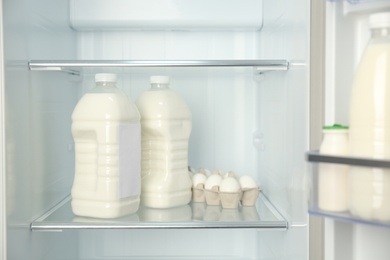 Photo of Gallons of milk near eggs in refrigerator, closeup