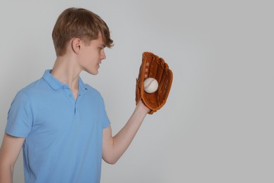 Photo of Teenage boy with baseball ball on light grey background. Space for text