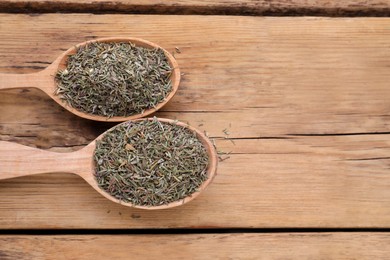 Spoons with dried thyme on wooden table, flat lay. Space for text