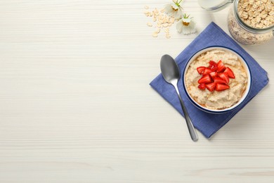 Tasty oatmeal porridge with strawberries served on white wooden table, flat lay. Space for text
