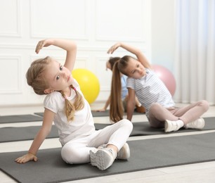 Photo of Group of children doing gymnastic exercises on mats indoors, selective focus