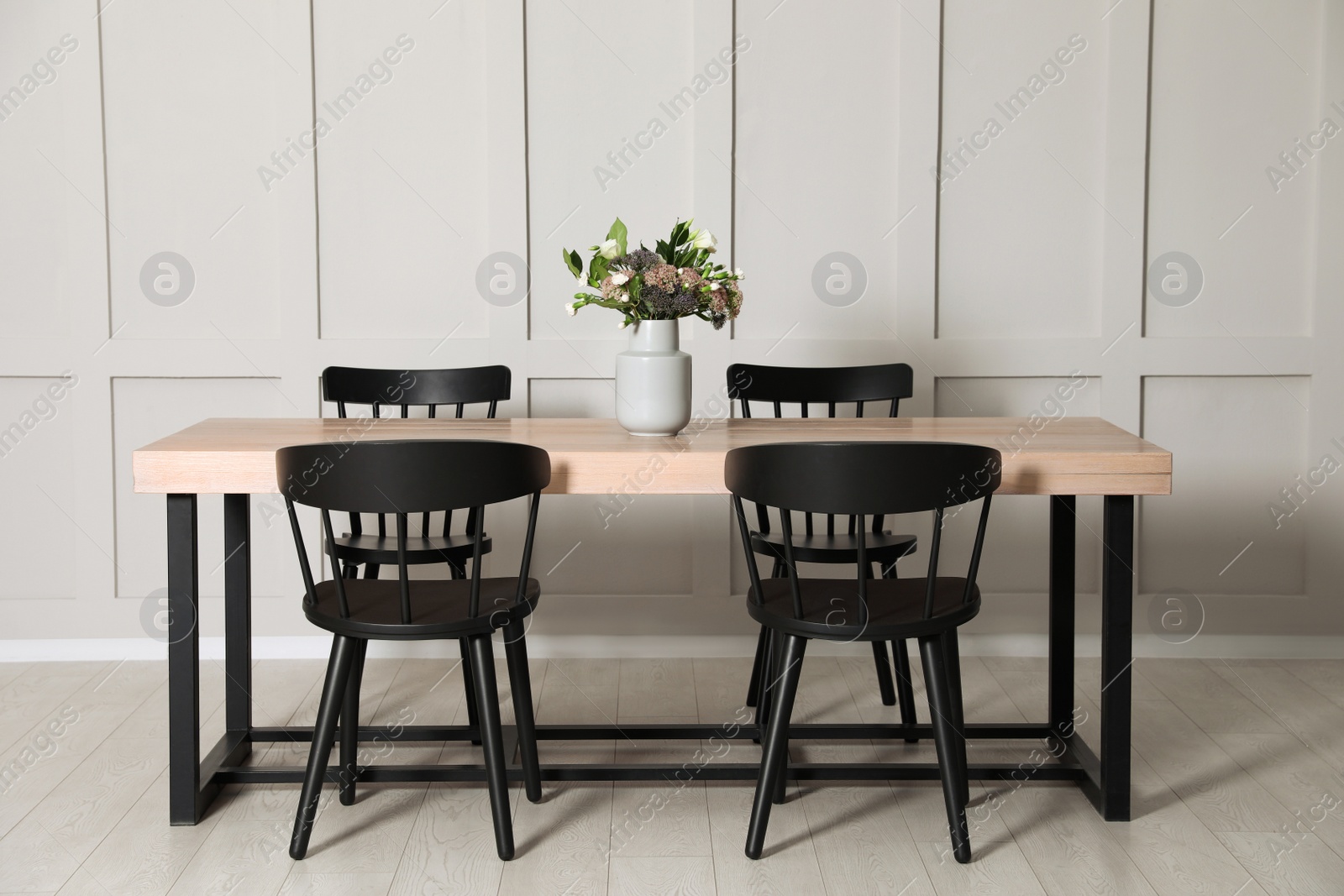 Photo of Stylish dining room interior with wooden table and chairs near molding wall