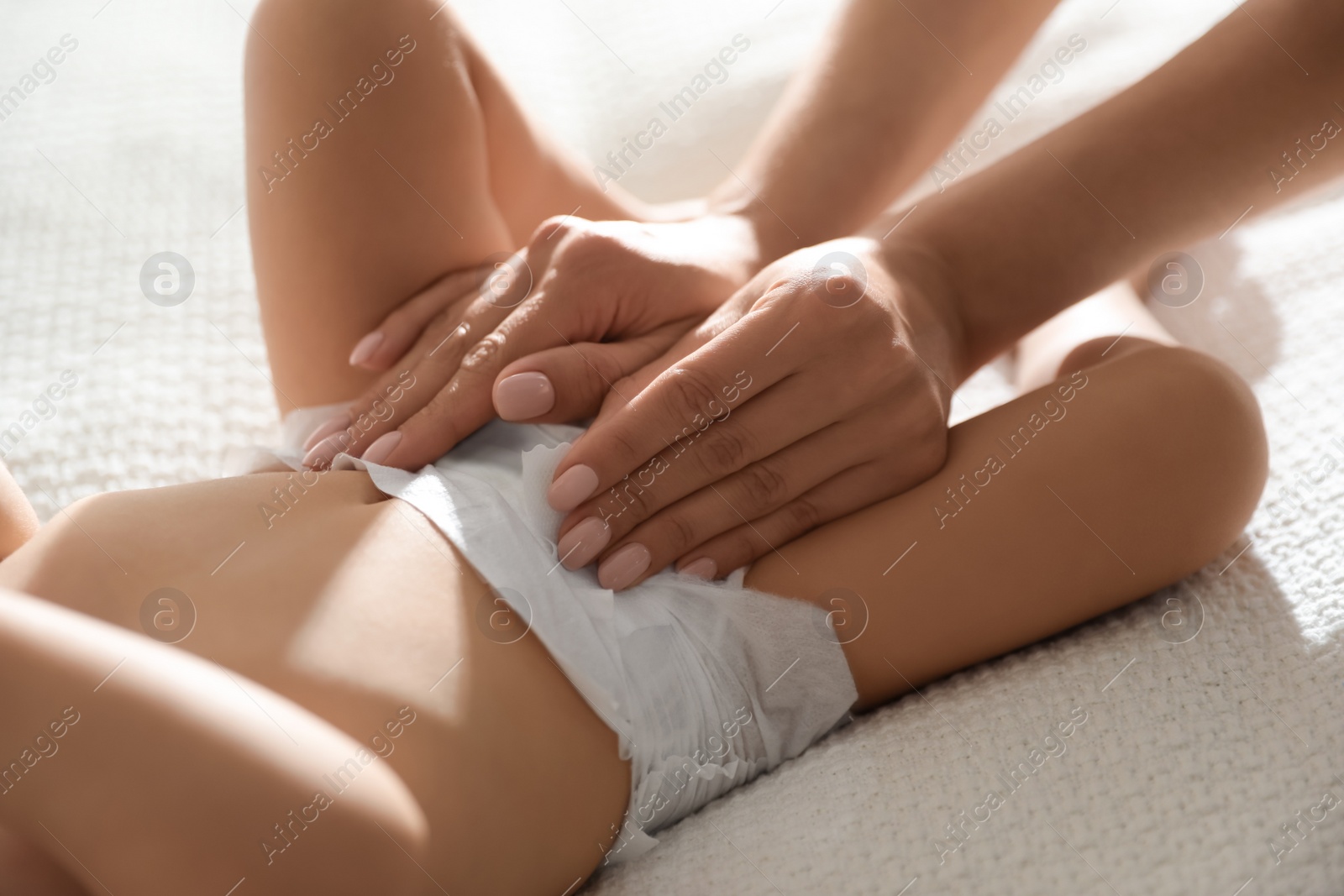 Photo of Mother changing baby's diaper on bed at home, closeup