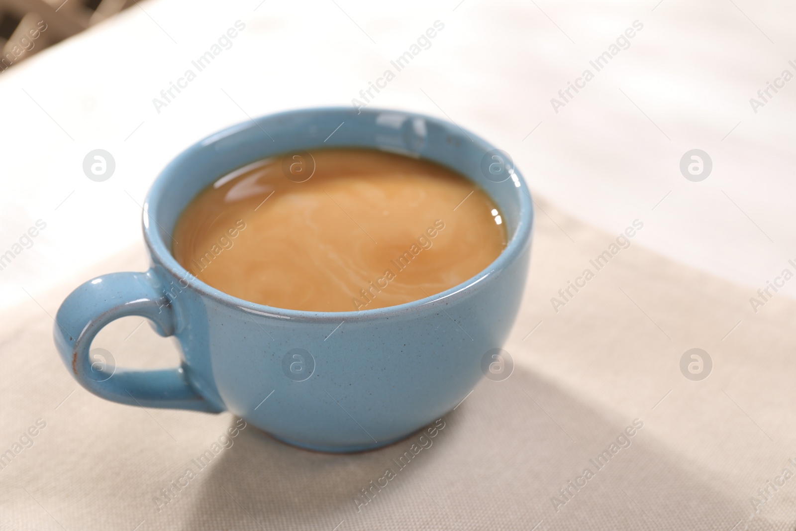Photo of Delicious coffee in cup on white table, closeup. Space for text