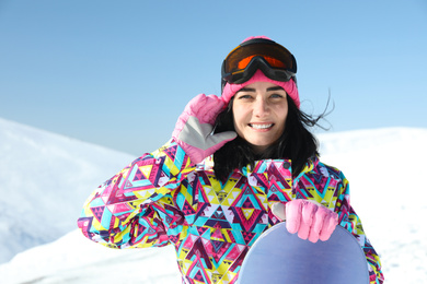 Photo of Happy young woman with snowboard in mountains. Winter vacation