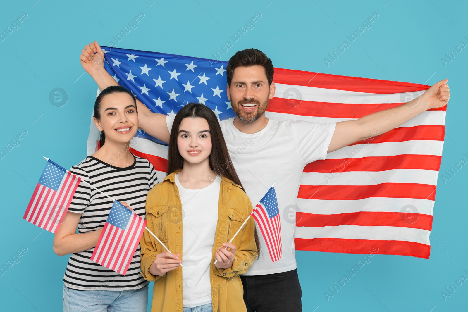 Photo of 4th of July - Independence Day of USA. Happy family with American flags on light blue background