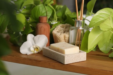 Photo of Composition with spa products and green houseplants on wooden table