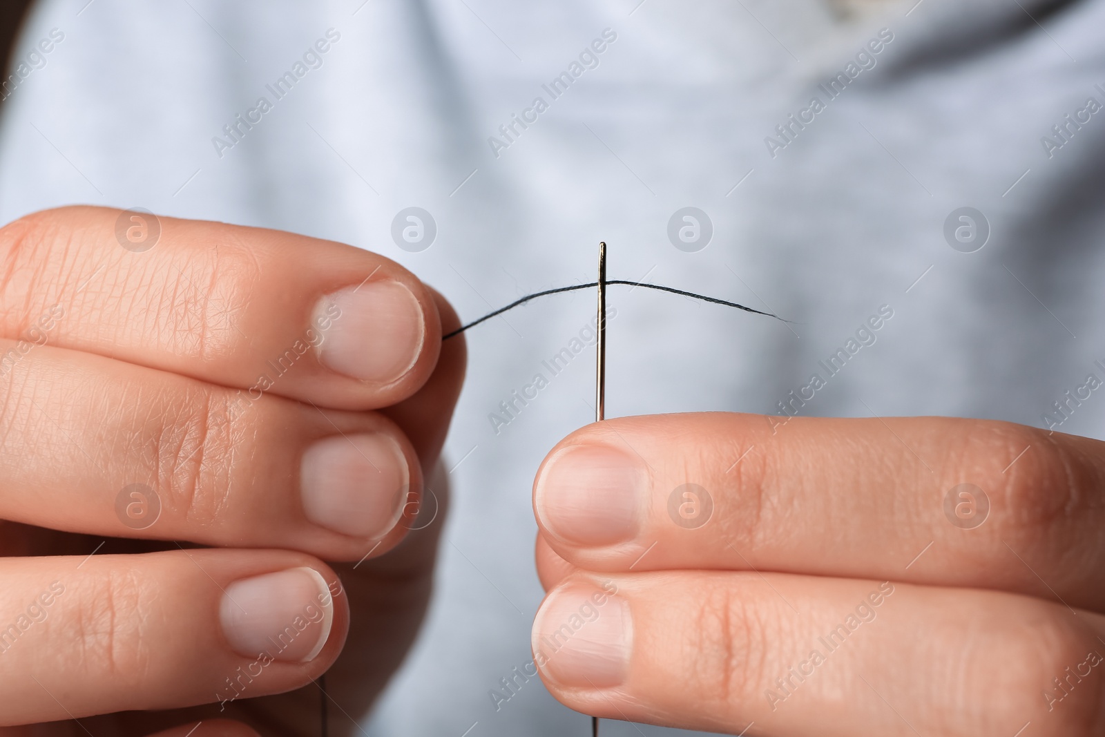 Photo of Closeup view of woman threading sewing needle