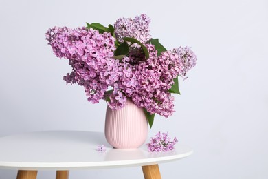 Photo of Beautiful lilac flowers in vase on white table