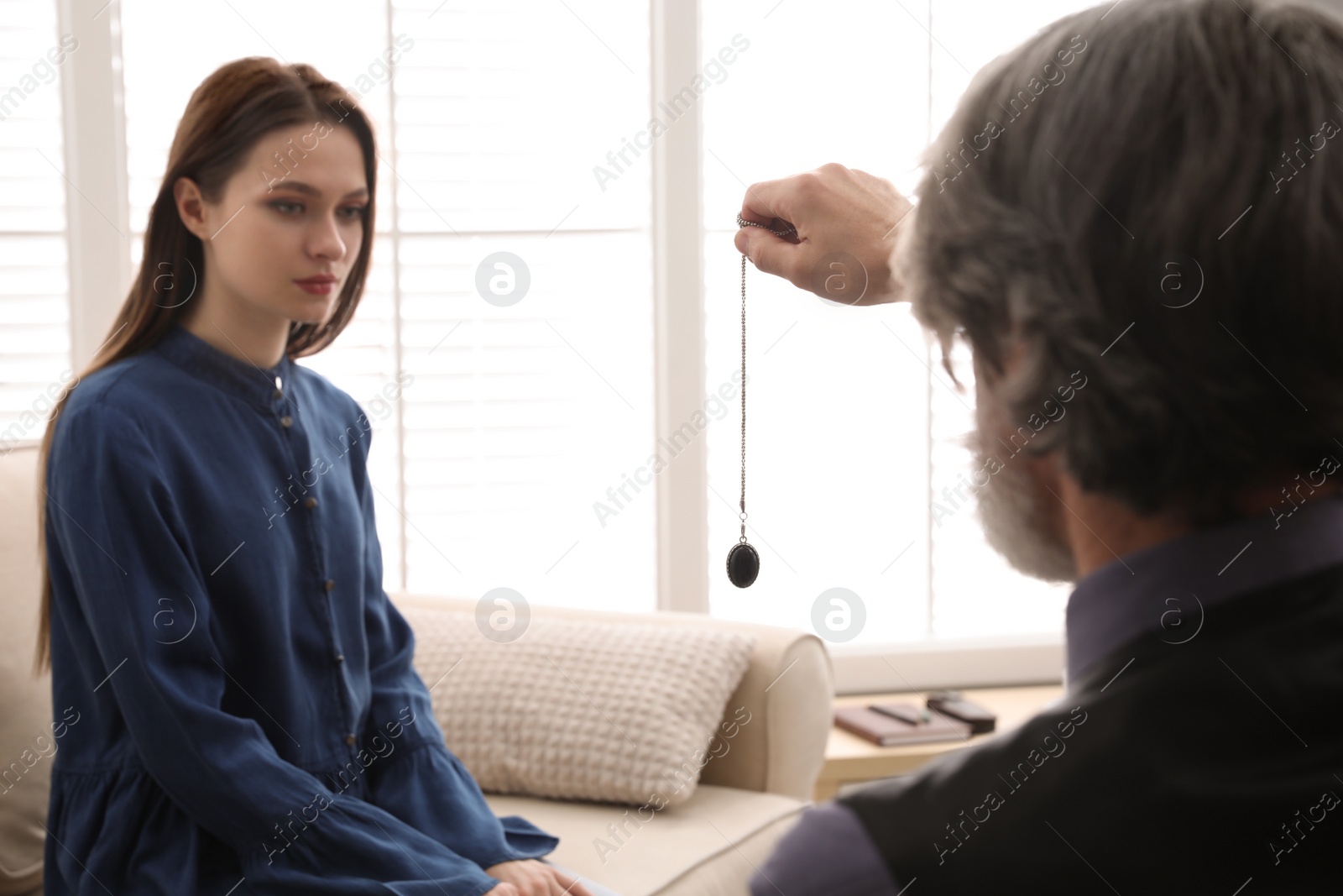 Photo of Psychotherapist using pendulum during hypnotherapy   session in office