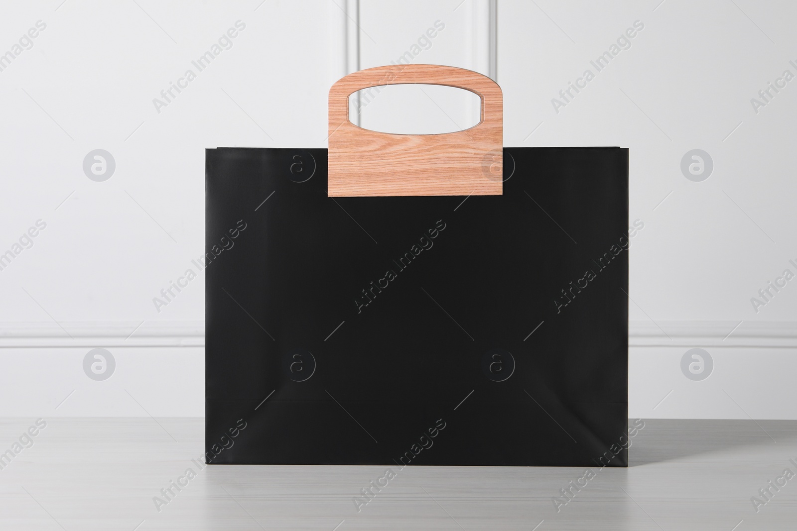 Photo of Black paper bag on white wooden table