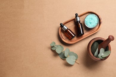 Photo of Aromatherapy products. Bottles of essential oil, sea salt, eucalyptus leaves and mortar on brown background, flat lay. Space for text