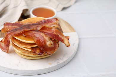 Delicious pancakes with bacon and honey on white table, closeup. Space for text