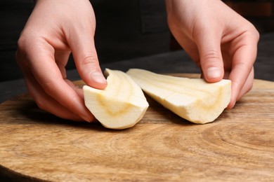 Photo of Woman with cut delicious fresh ripe parsnip at wooden board, closeup