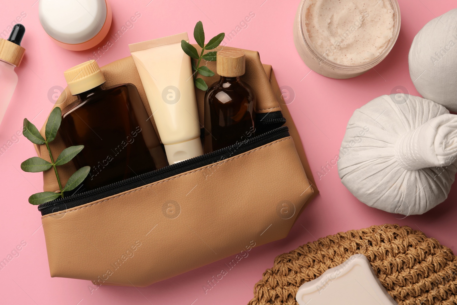 Photo of Preparation for spa. Compact toiletry bag with different cosmetic products and twigs on pink background, flat lay