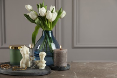 Photo of Beautiful sculptural candles, flowers and decor on grey table. Space for text