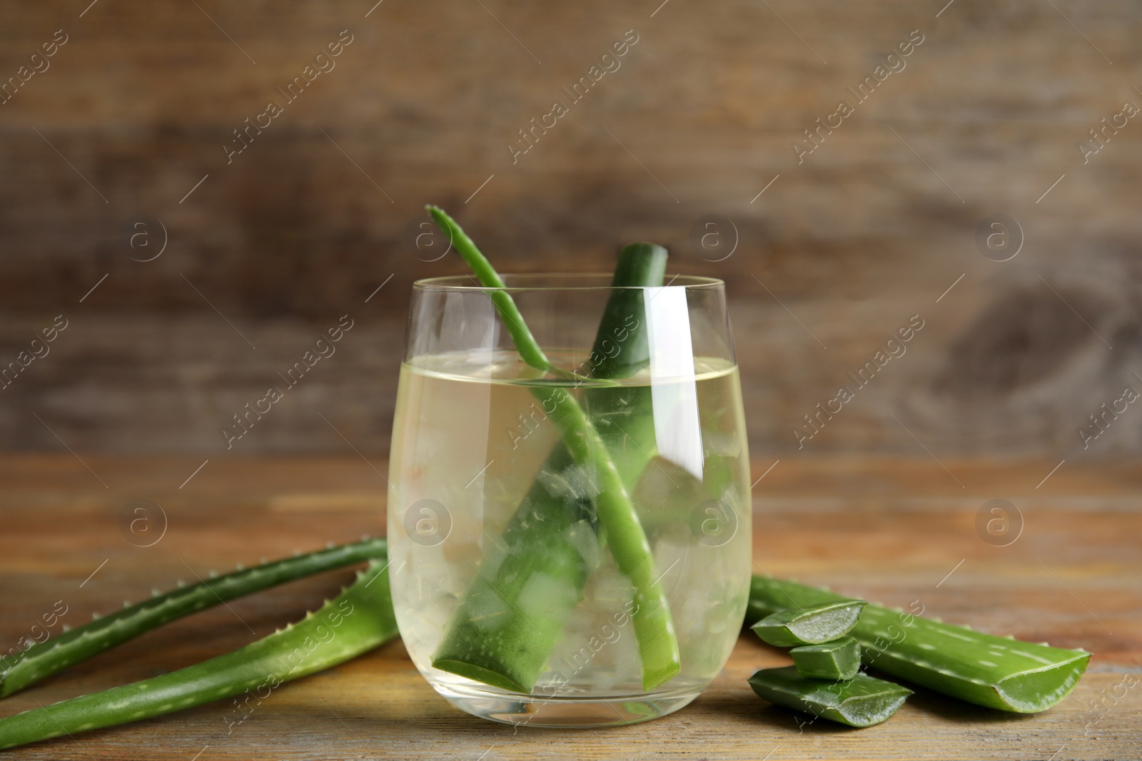 Photo of Fresh aloe drink with leaves in glass on wooden table