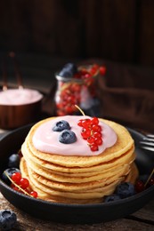 Photo of Tasty pancakes with natural yogurt, blueberries and red currants on wooden table