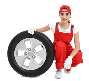 Female mechanic in uniform with car tire on white background