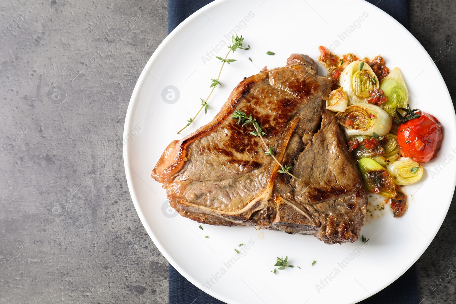 Photo of Delicious fried beef meat and vegetables on grey table, top view