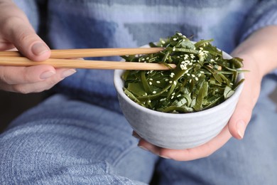 Woman eating fresh laminaria (kelp) seaweed, closeup