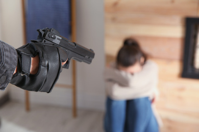 Man aiming his victim with gun indoors, closeup. Dangerous criminal