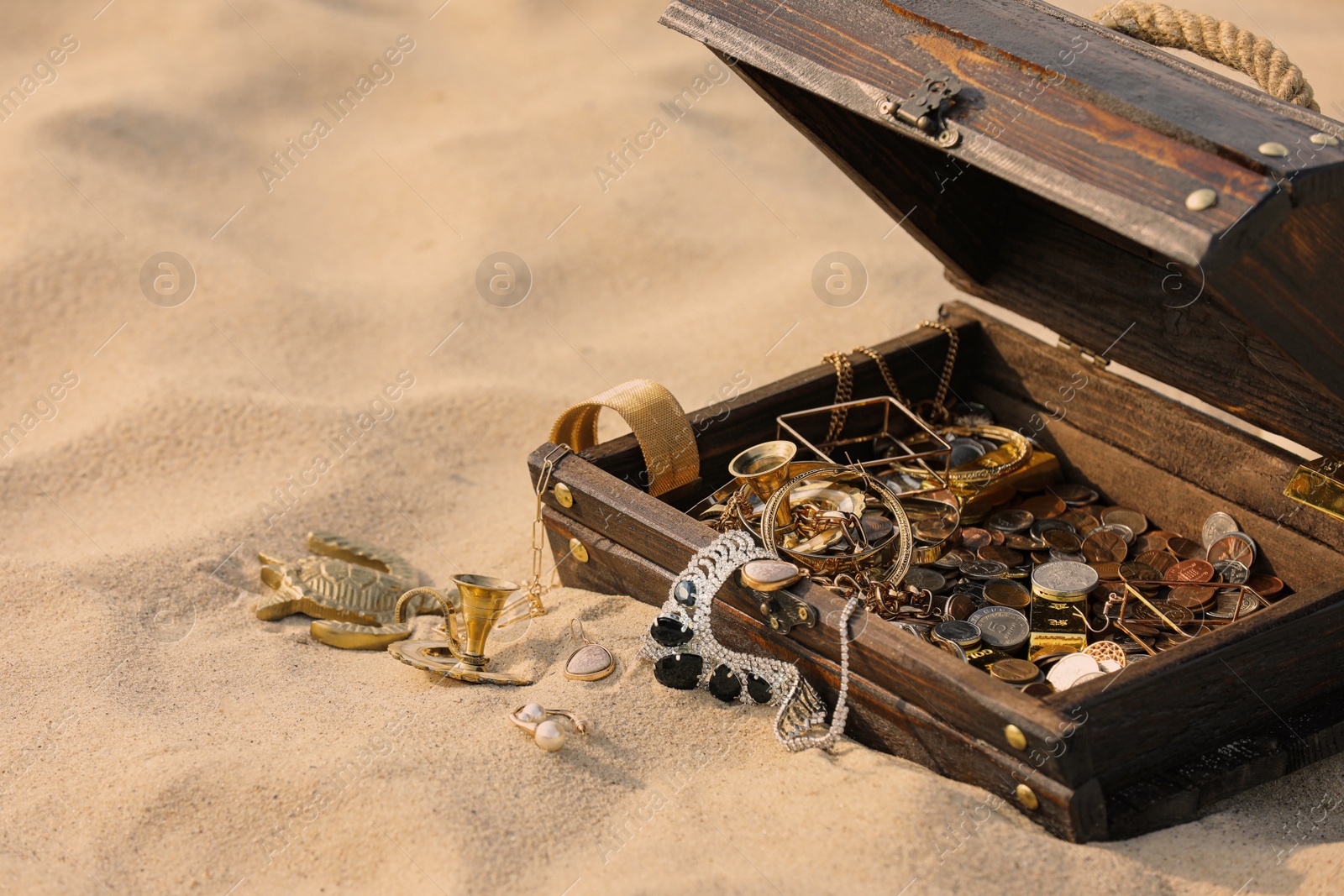 Photo of Open wooden treasure chest on sand, space for text