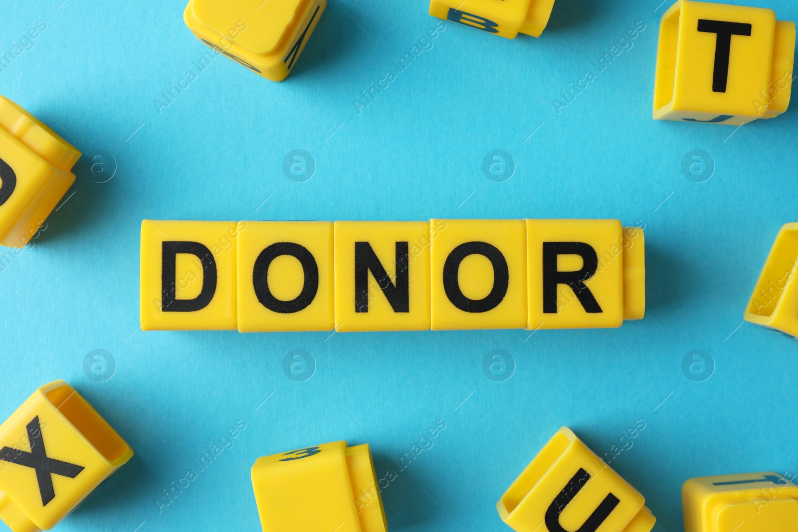 Photo of Word Donor made of cubes on light blue background, flat lay