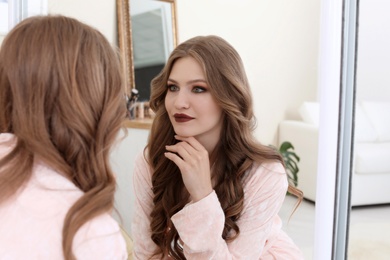 Photo of Young beautiful woman near mirror in makeup room