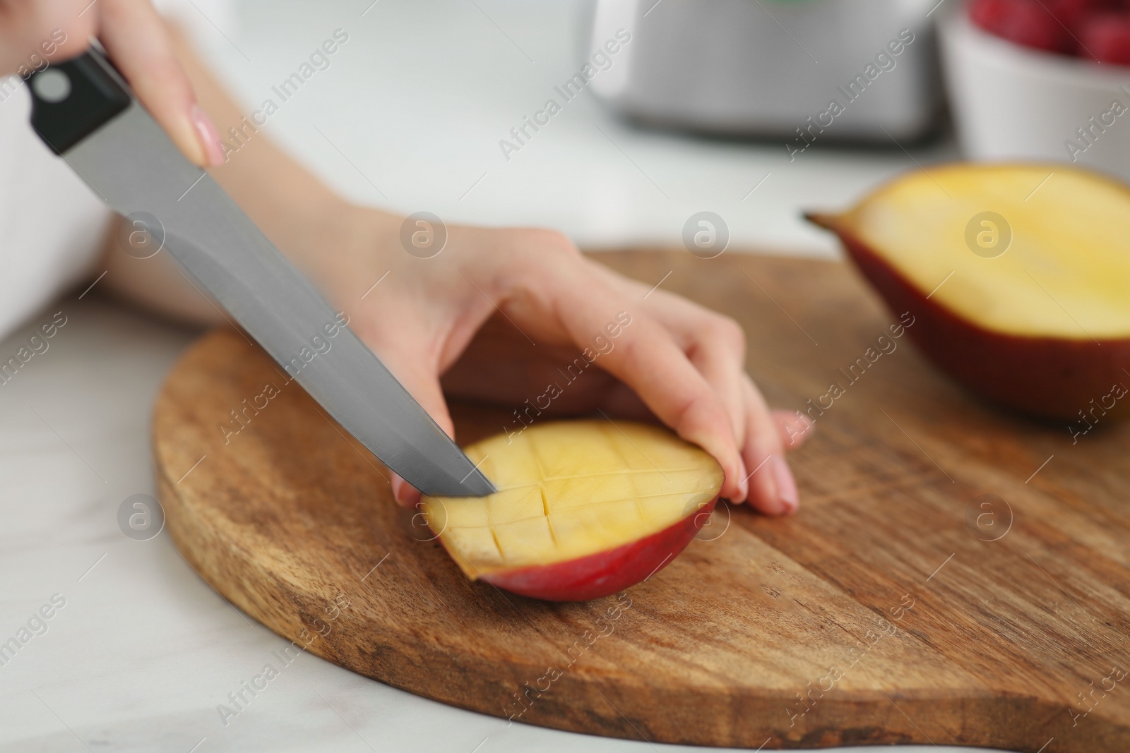 Photo of Woman preparing mango for tasty smoothie at white marble table, closeup