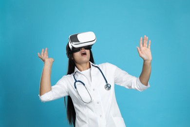 Photo of Emotional female doctor using virtual reality headset on light blue background