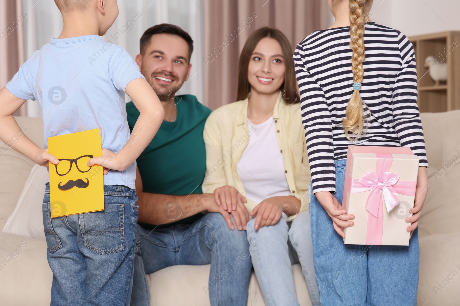 Photo of Little children presenting their parents with gifts at home