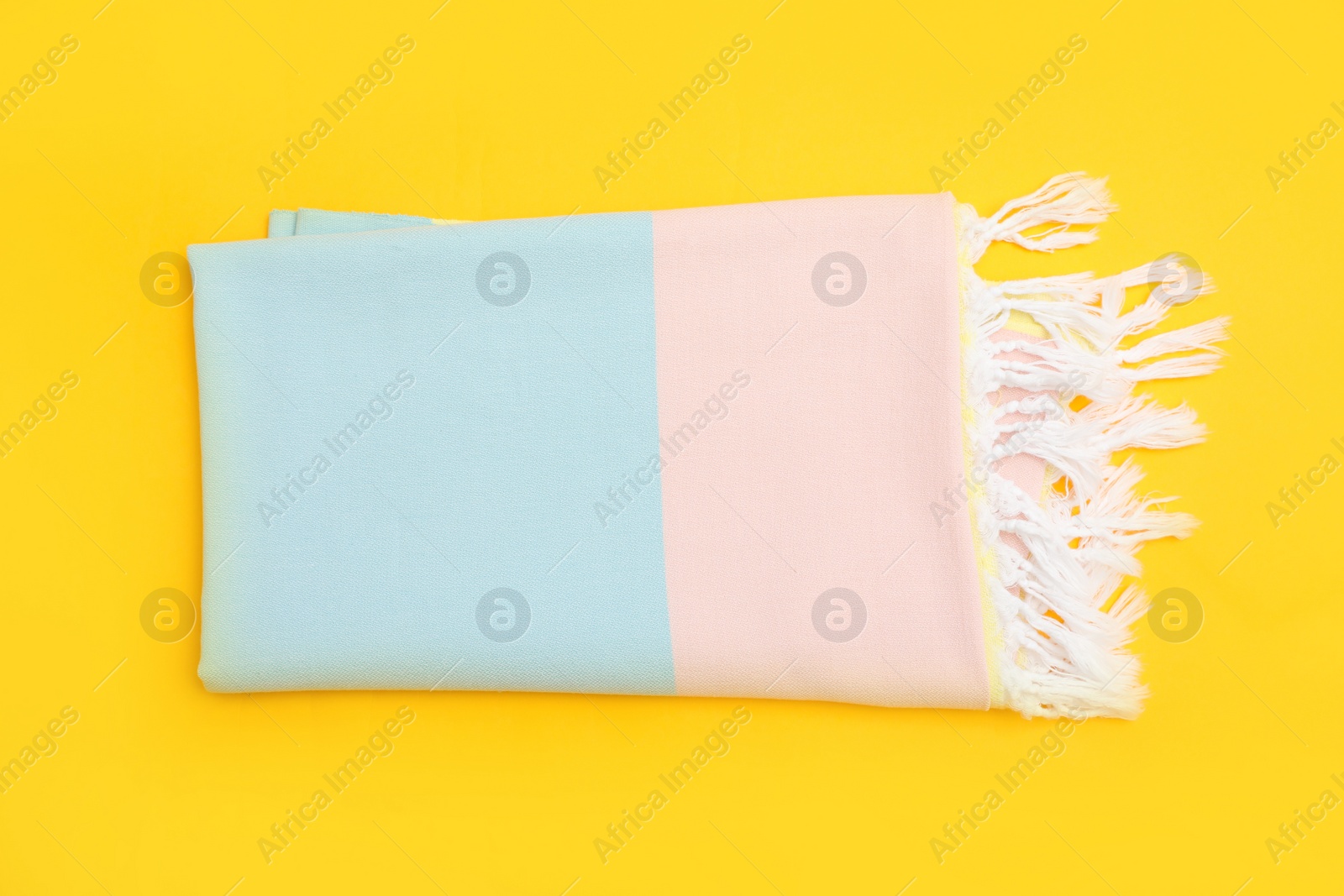 Photo of Folded striped beach towel on yellow background, top view