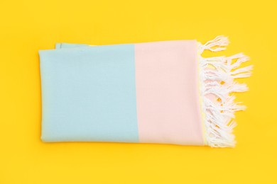 Photo of Folded striped beach towel on yellow background, top view